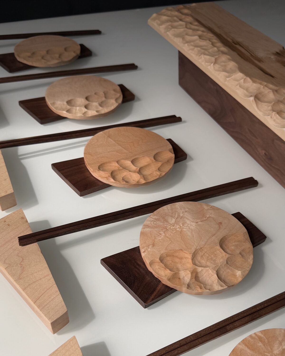 Place settings at an angle — carved maple dishes on walnut bases, with chopsticks