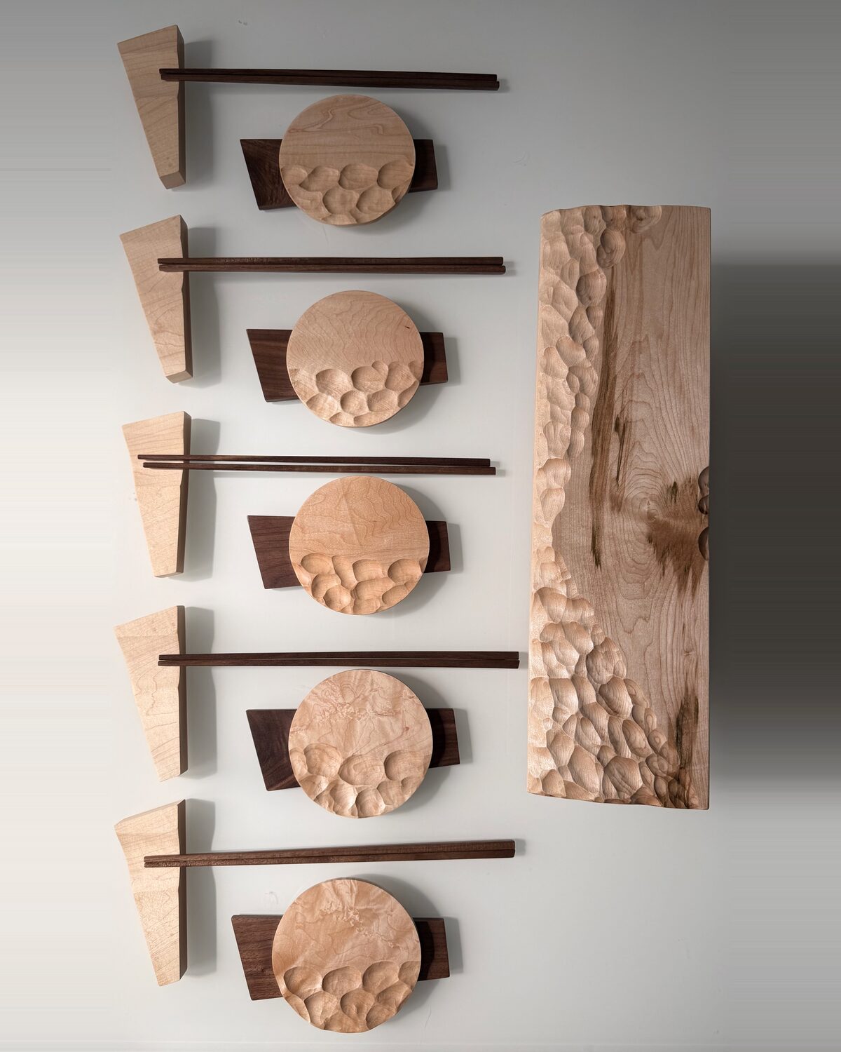 Seen from above — carved maple dishes, chopsticks and the long carved board