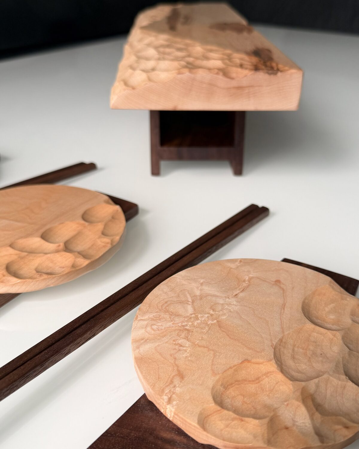 A large carved maple dish raised on a walnut base