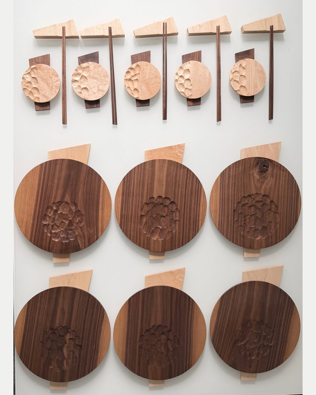 The collection laid out — carved maple dishes above, carved walnut below