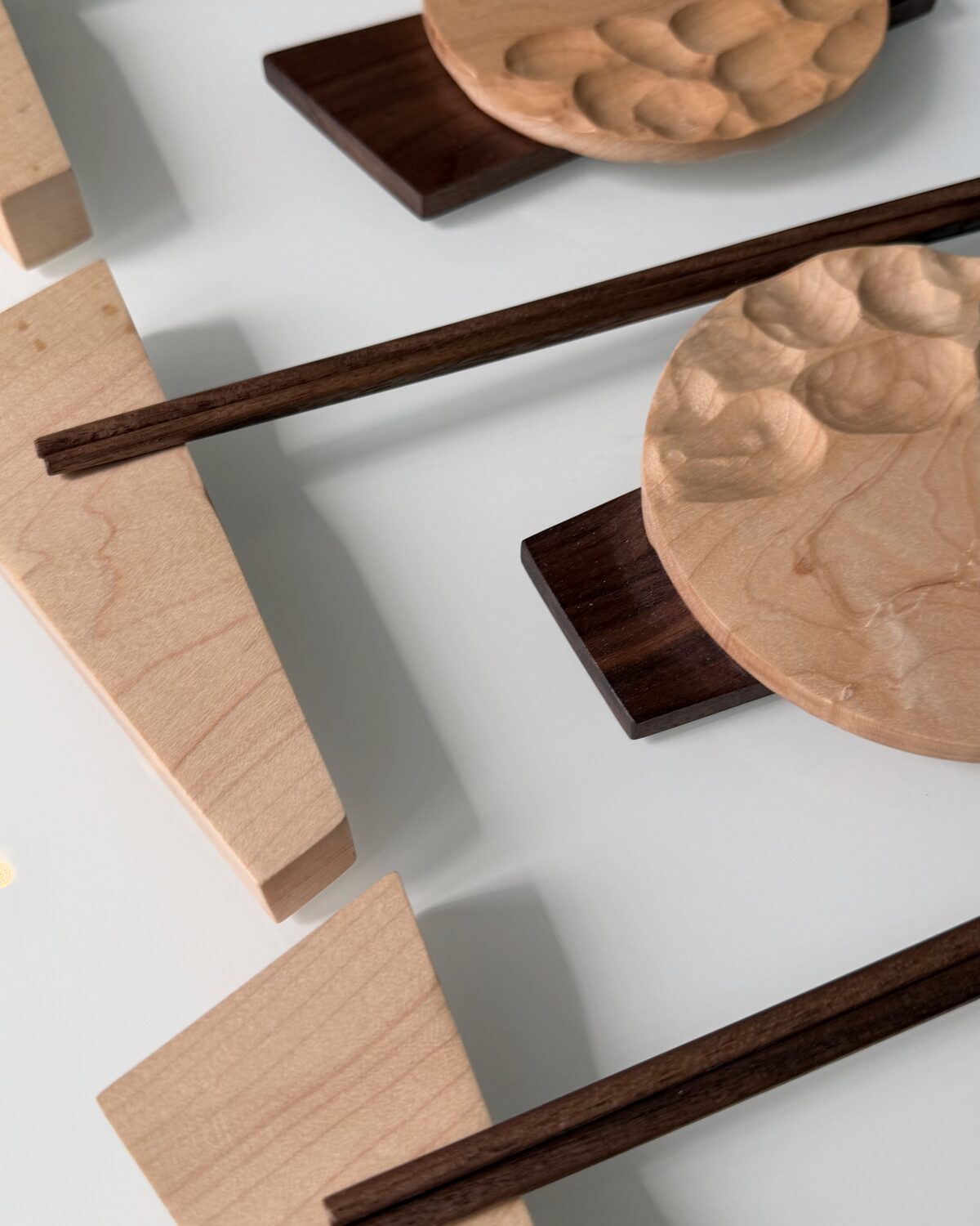 Place settings in soft light — a carved maple dish on its walnut base
