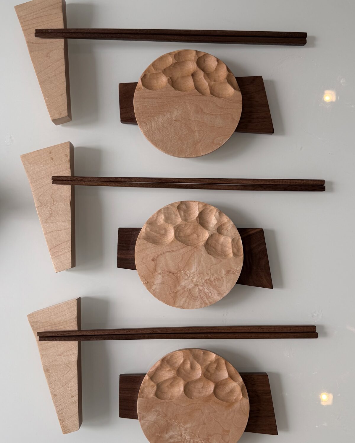 Three place settings from above, each with chopsticks and a maple rest