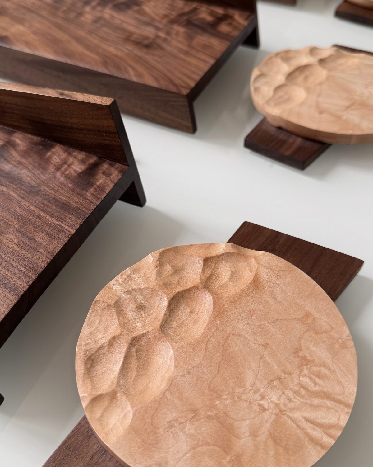 A carved maple dish on its walnut base, boards behind