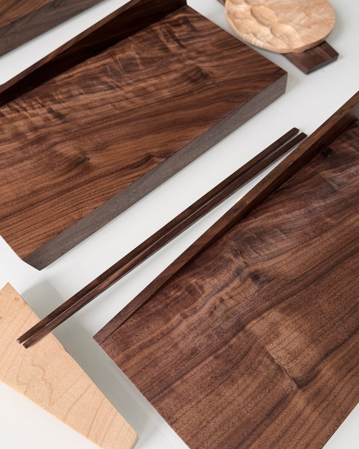 A figured walnut board with walnut chopsticks and a maple rest
